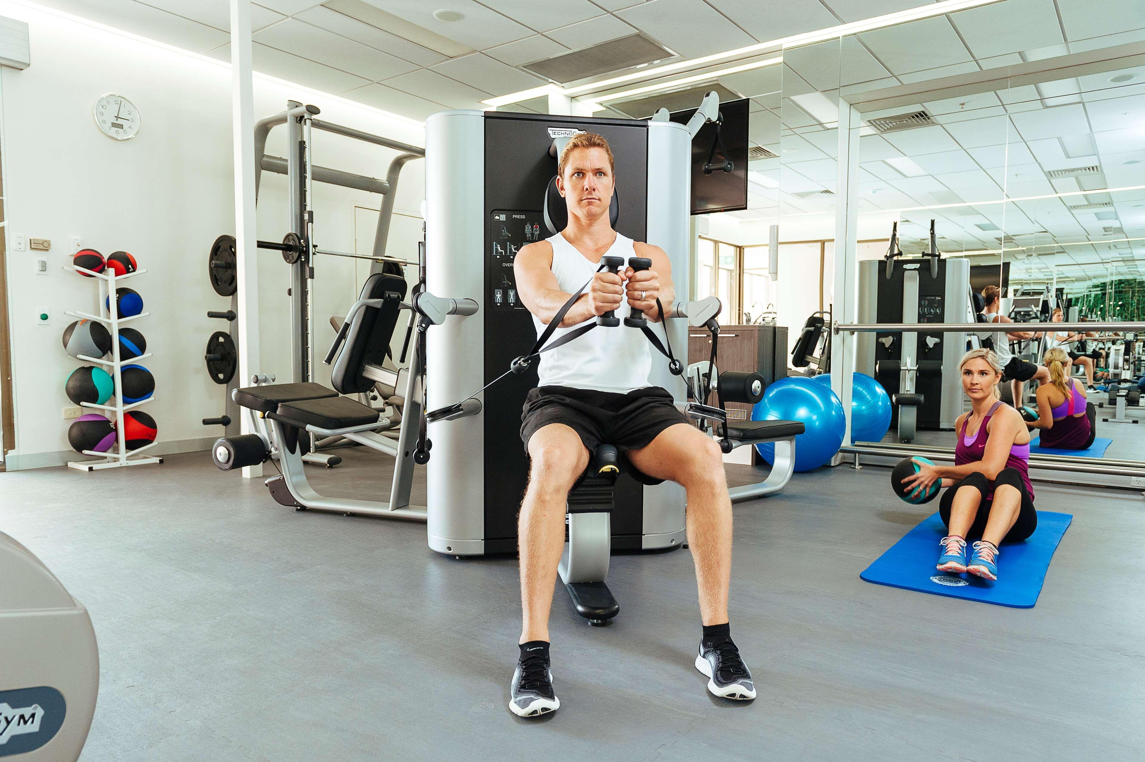 Stamford Plaza Adelaide Otel Dış mekan fotoğraf The photo shows a gym setting with two individuals engaged in workout activities. 

In the foreground, a man is seated on a machine, using the handles to perform a rowing exercise. He is wearing a sleeveless shirt and shorts, indicating an active wor
