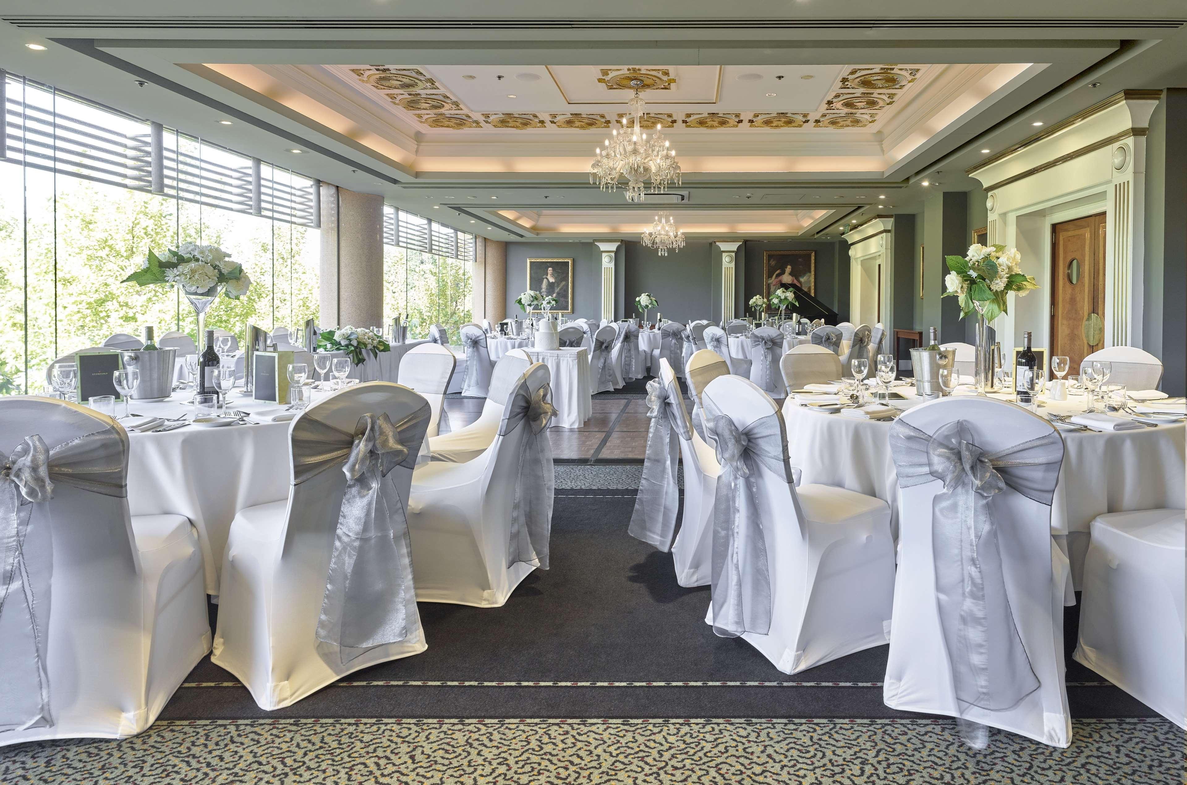 Stamford Plaza Adelaide Otel Dış mekan fotoğraf The photo displays an elegantly arranged banquet hall. The room features several round tables covered with white tablecloths, each adorned with silver sashes on the chairs. There are floral centerpieces, possibly white flowers, on the tables, adding 