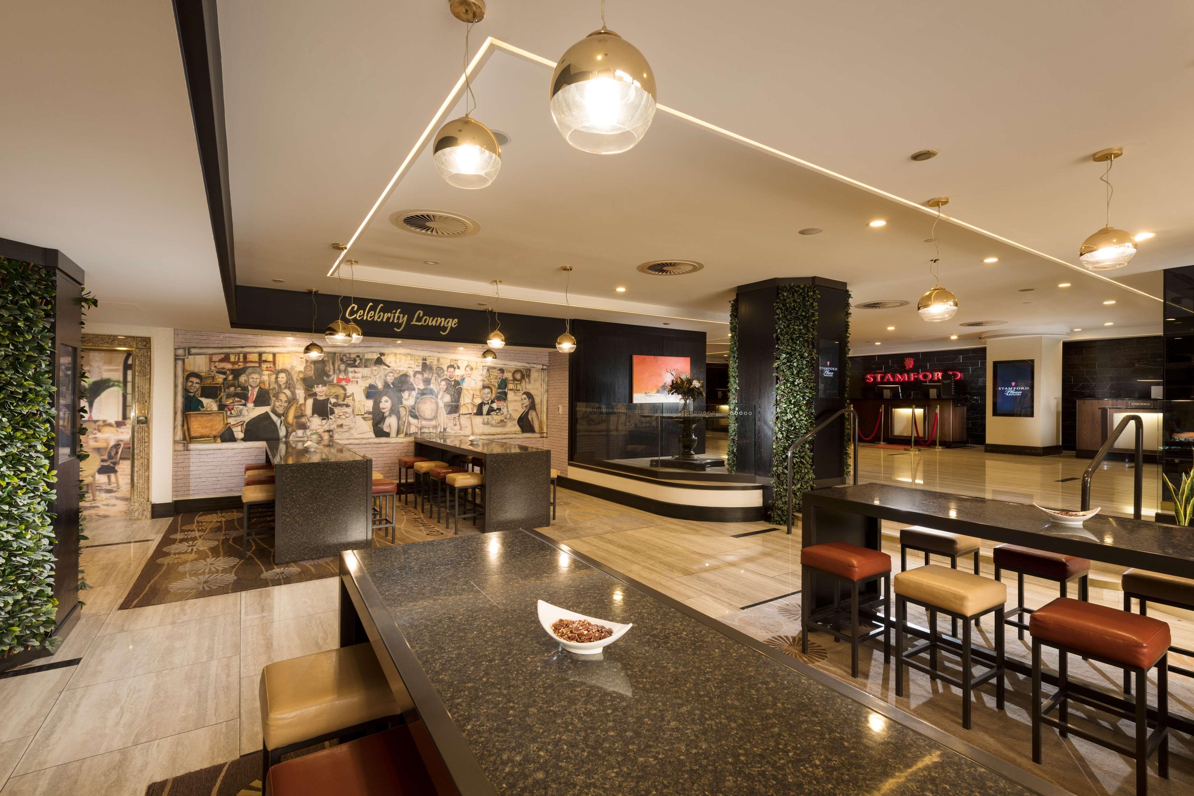 Stamford Plaza Adelaide Otel Dış mekan fotoğraf The photo shows a modern and stylish interior of a lounge or restaurant area. Prominent features include a long dark countertop with bar stools, and several pendant lights hanging from the ceiling. In the background, there is a mural or artwork that 